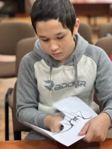 Хлопчик вирізає з паперу зображення кажана