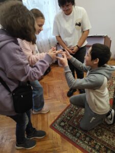 Діти намагаються втримати вказівними пальцями лінійку і присісти з нею